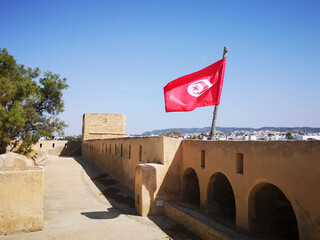 Tunisian National Flag flying from the Old Medina in Hammammet. The crescent and star depicted on the flag of Tunisia are traditional symbols of Islam, and are also considered symbols of good luck.