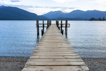 Pier projecting into lake with mountain range background