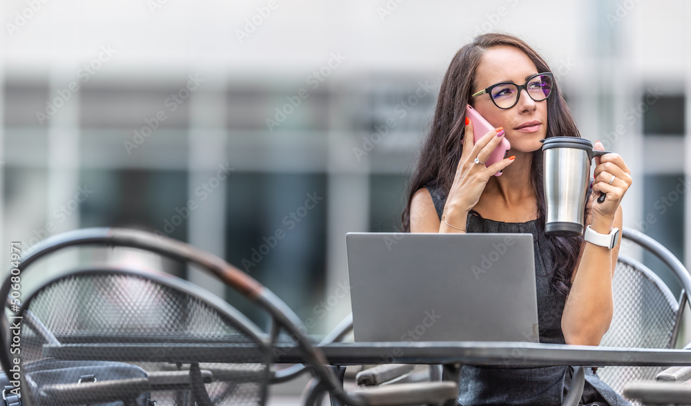 Canvas Prints Businesswoman holds cofee mug listening to a person on a phone with opened computer in front of her