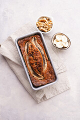 Chocolate banana bread with walnuts in a metallic baking mold on a grey neutral background, top view