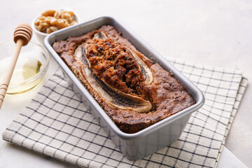 Chocolate banana bread with walnuts in a metallic baking mold on a grey neutral background