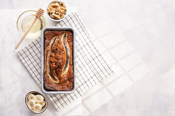 Chocolate banana bread with walnuts in a metallic baking mold on a grey neutral background, top...