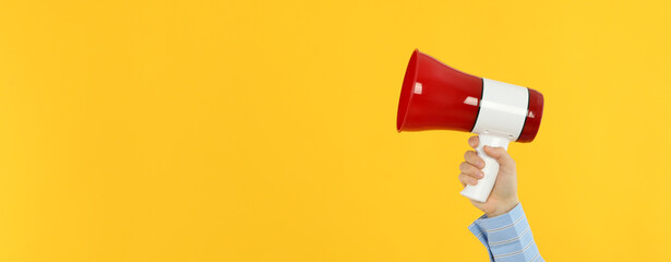 Female hand with megaphone on yellow background
