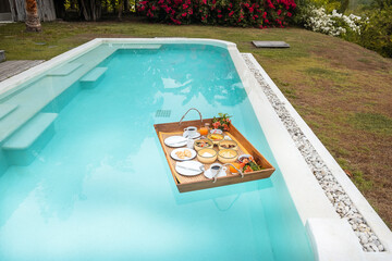 Floating Breakfast tray in swimming pool at luxury hotel or tropical resort villa, fruits,...