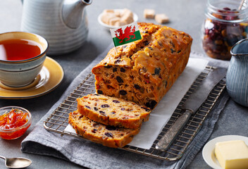 Loaf cake Bara Brith with Wales flag. Welsh traditional dessert with cup of tea. Grey background. Close up.