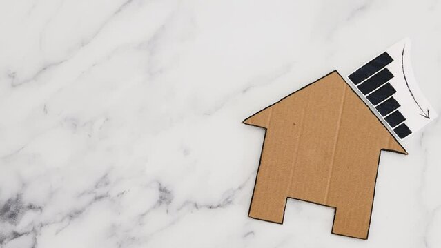 mortgages rentals and property prices decreasing, house icon made of cardboard with graph showing stats going down