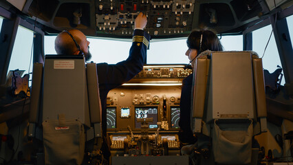 Male captain fixing altitude and longitude levels to fly airplane, using control panel command to...