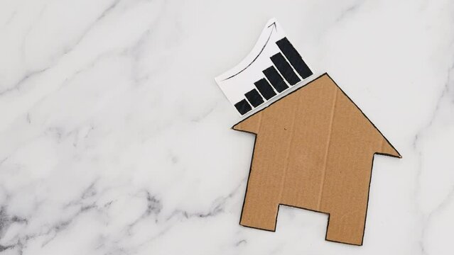 mortgages rentals and property prices increasing, house icon made of cardboard with graph showing stats going up