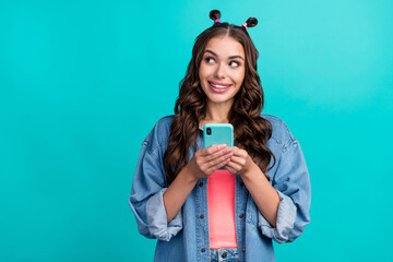 Photo of young lovely lady wonder look empty space comment blogging use mobile isolated over turquoise color background