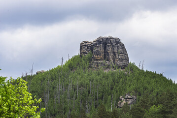 Beautiful view of the landscape of Bohemian Switzerland. The photo shows meadows, forests and especially the rocks that protrude between the trees in the photo. The forest is a mix of different trees.