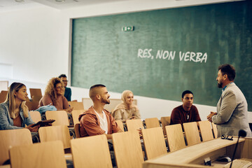 Group of happy university students listening to their professor during lecture in classroom.