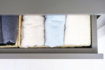 Folded towels in a wicker box in dresser close-up, space organization concept.