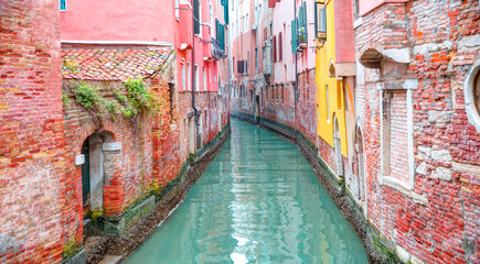 Narrow canal with red brick houses -  Venice, Italy