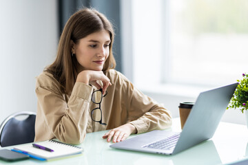 Portrait of a businesswoman sitting on her workplace in the office, typing, looking at pc screen.