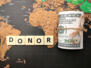 Toys word and banknotes with the word DONOR on a world map background.