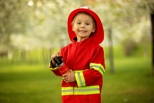 Little toddler child with fireman costume in park, pretending to be real fireman, playing