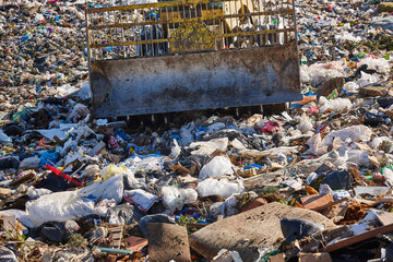 Heavy machinery shredding garbage in an open air landfill. Pullution