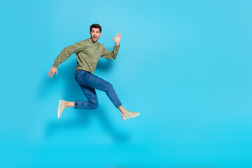 Fototapeta na wymiar Full body photo of satisfied glad young person enjoy running jump isolated on blue color background