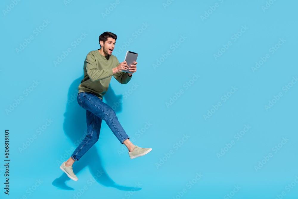 Poster full length profile portrait of impressed energetic person use tablet isolated on blue color backgro
