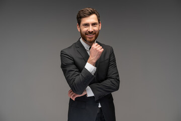 Portrait of cheerful businessman sincerely smiling at camera, having positive mood. Indoor studio shot, isolated on grey background