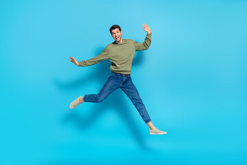 Fototapeta premium Full length photo of cheerful sporty person good mood jumping isolated on blue color background