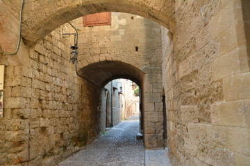 Fototapeta na wymiar narrow medieval street with brick walls and arched entrances and stone path