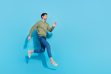 Full length photo of cute millennial brunet guy run wear shirt jeans sneakers isolated on blue background