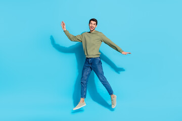 Fototapeta na wymiar Full body portrait of satisfied glad young man enjoy free time jump isolated on blue color background