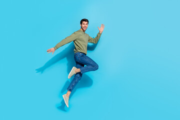 Full length photo of funky millennial brunet guy run wear shirt jeans sneakers isolated on blue color background
