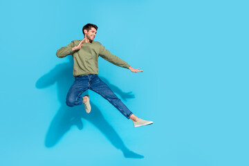 Fototapeta na wymiar Full size portrait of sportive excited person jump air battle hands legs kick isolated on blue color background