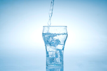 Ice cube fell into the glass of water.Water splashed from the clear glass.Fresh concept