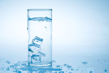 Ice cube fell into the glass of water.Water splashed from the clear glass.Fresh concept