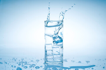 Ice cube fell into the glass of water.Water splashed from the clear glass.Fresh concept