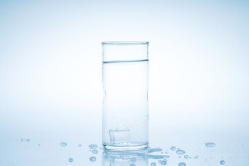 Ice cube fell into the glass of water.Water splashed from the clear glass.Fresh concept