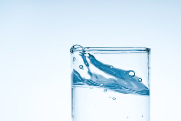 Ice cube fell into the glass of water.Water splashed from the clear glass.Fresh concept