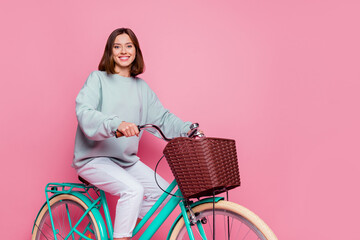 Profile side photo of young pretty cheerful girl enjoy riding bicycle isolated over pink color...