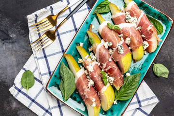 Appetizer with pear, blue cheese and prosciutto ham on a dark background, Healthy fats, clean eating for weight loss, Long banner format. top view