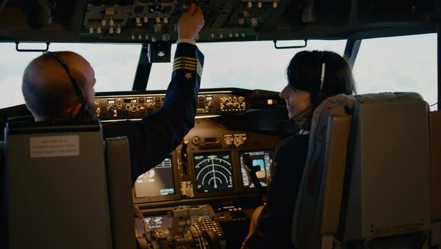 Plane captain and female copilot switching altitude and longitude level to takeoff. Flying transportation airplane with radar compass, power engine and control panel command. Handheld shot.