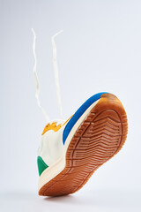 White colorful sport sneakers with flying shoe lace gray background, Casual trendy shoes closeup,...