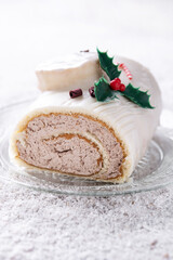 White chocolate yule log cake with ornament on white wooden table