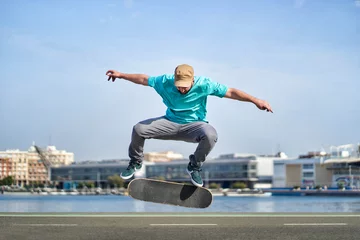 Fotobehang a man doing an ollie flip with his skateboard down a road © Retamosa