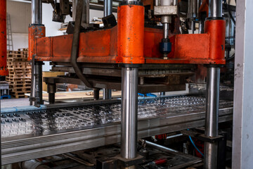 Vacuum thermoforming machine is used for producing plastic packaging in the factory. Close-up of the machine making a mold. Selective focus front