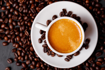Hot fresh black coffee with milk foam for morning menu in white ceramic cup with coffee beans roasted on.