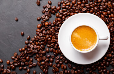 Hot fresh black coffee with milk foam for morning menu in white ceramic cup with coffee beans roasted on.