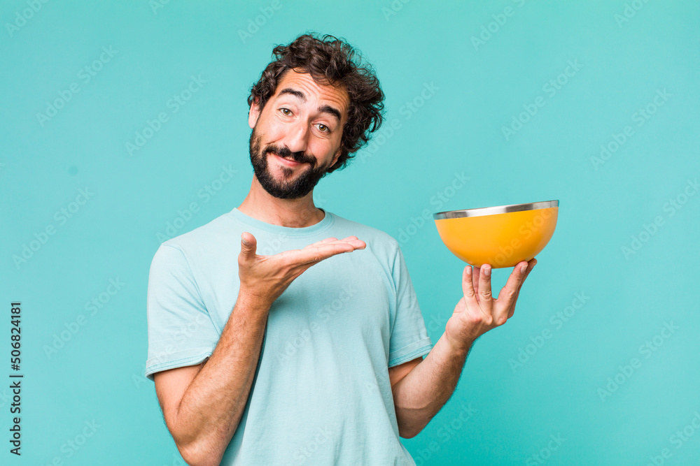 Poster young adult hispanic crazy man holding an empty bowl