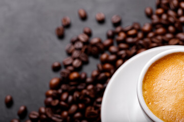 Hot fresh black coffee with milk foam for morning menu in white ceramic cup with coffee beans roasted on.