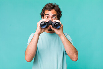 young adult hispanic crazy man with binoculars. searching concept