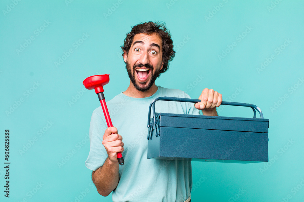 Wall mural young adult hispanic crazy man with a toolbox. handyman concept - Wall murals