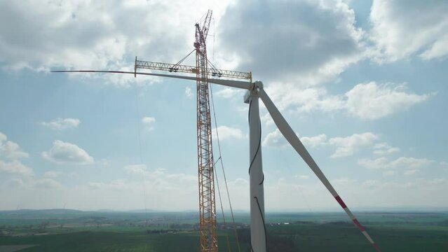 The wind farm during construction, the crane lifts a huge propeller, which the fitter sitting upstairs will tighten.