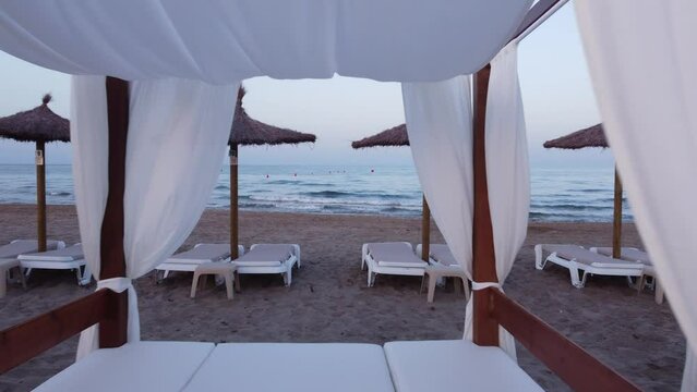 Bonito v&iacute;deo horizontal en 4k, con vistas al mar, en una playa con sombrillas y camas balinesas.